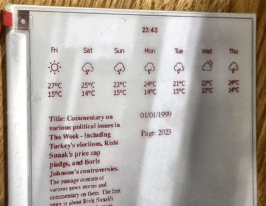 The e-paper display in the notebook cover, showing a seven-day weather forecast in red across the top with icons and temperatures, and below it a generated title and summary paragraph about recent news, with a date and page number in the margin.